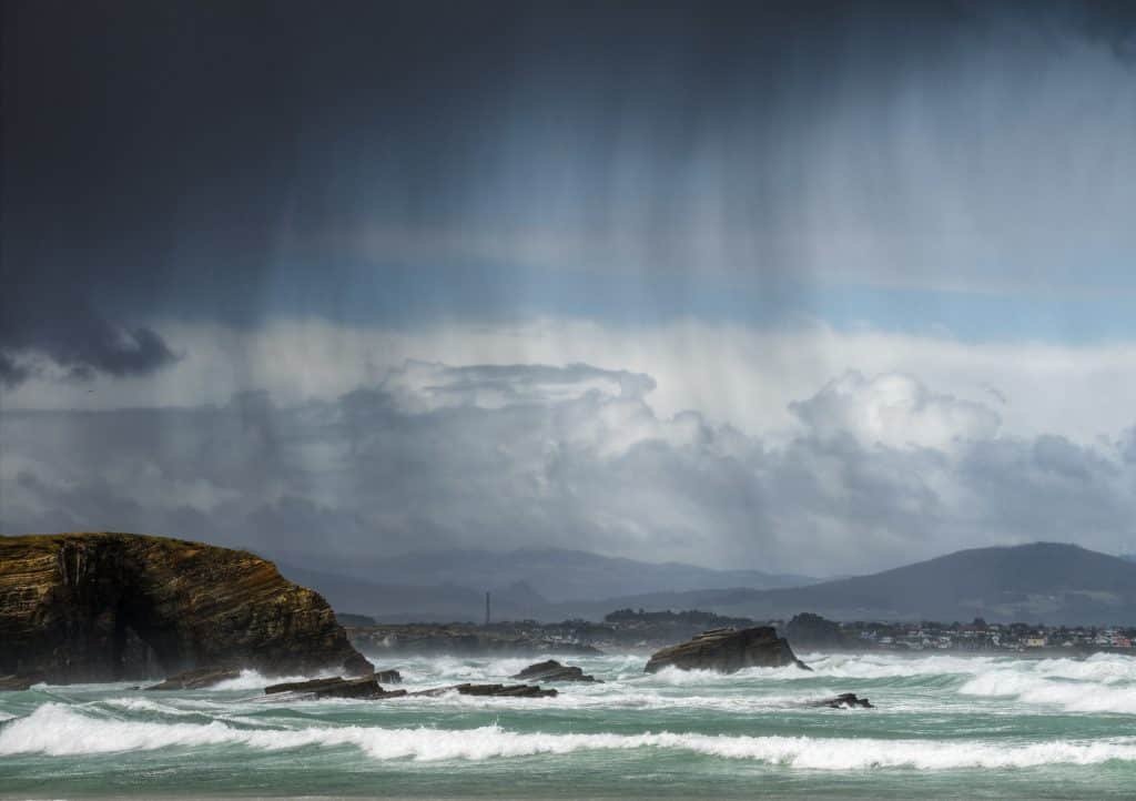 Rain showers blown by the wind between the sea and the cliffs