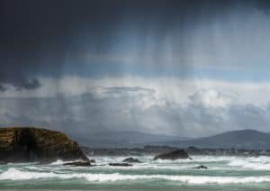 Rain showers blown by the wind between the sea and the cliffs
