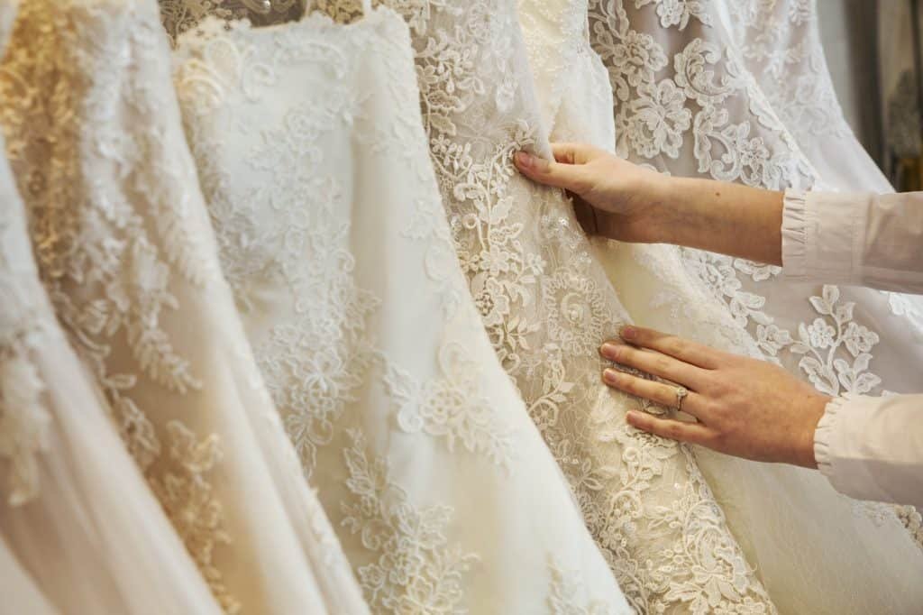 Rows of wedding dresses on display in a specialist wedding dress shop. Close up of full skirts, some