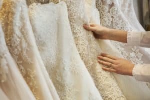 Rows of wedding dresses on display in a specialist wedding dress shop. Close up of full skirts, some