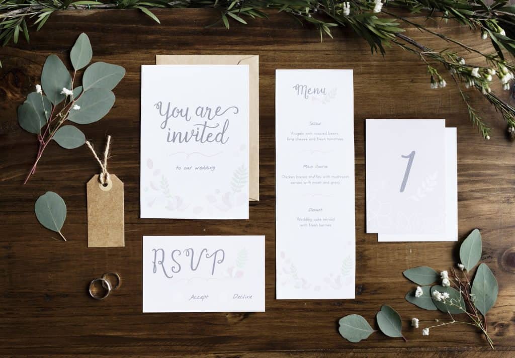 Wedding Invitation Cards Papers Laying on Table Decorate With Le