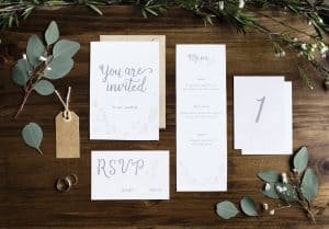 Wedding Invitation Cards Papers Laying on Table Decorate With Le
