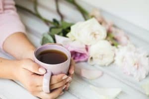 woman holding hot cup of tea on a wooden background. Morning, drink, break