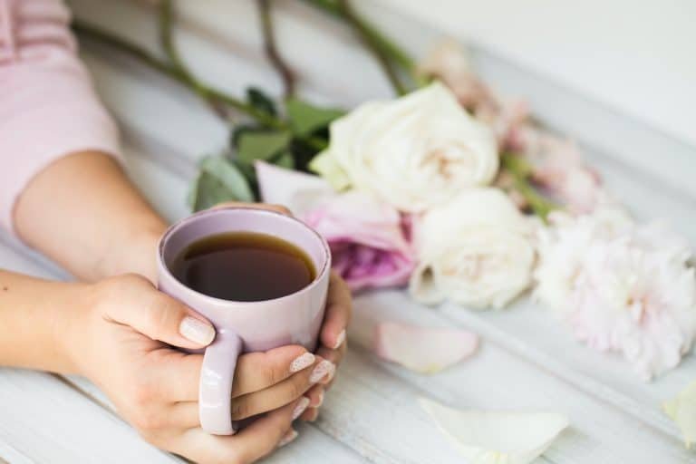 woman holding hot cup of tea on a wooden background. Morning, drink, break