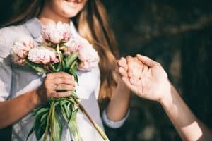 woman with engagement ring and peony bouquet